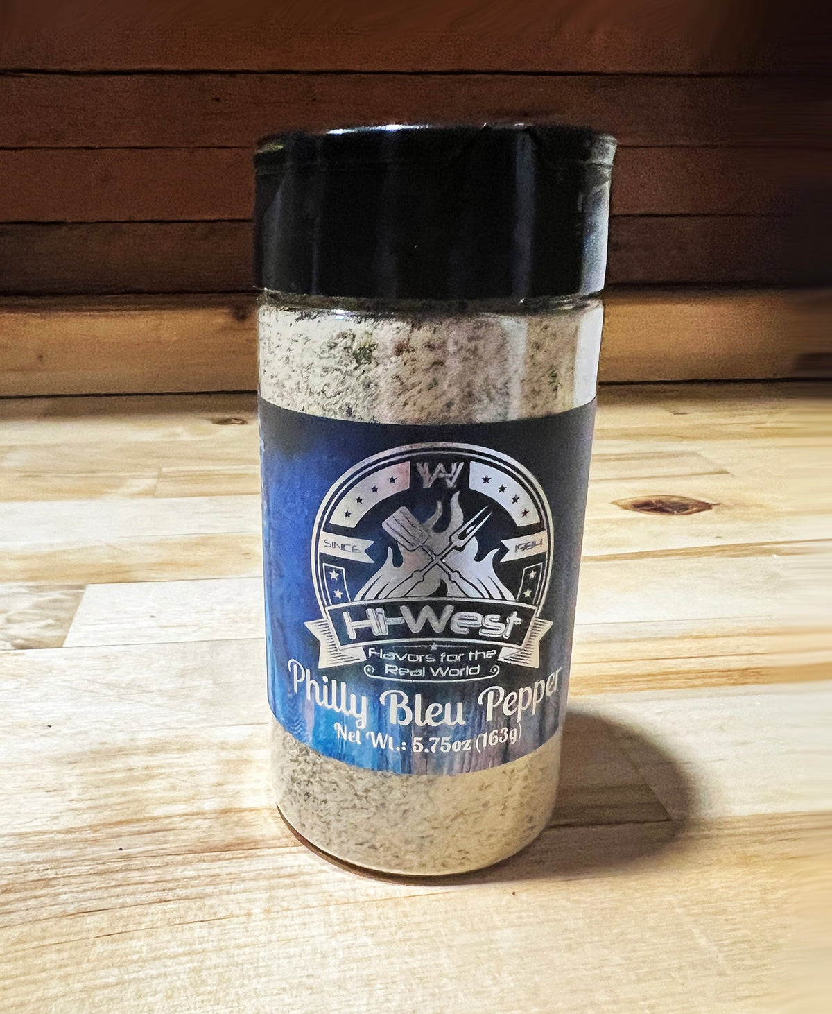 Hi-West Philly Bleu Pepper seasoning jar with blue label and black lid, featuring crushed blue peppercorns for flavorful spice.