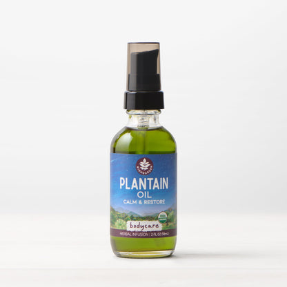 Bottle of WishGarden Herbs Plantain Oil for body care, with plantain leaves and natural ingredients visible in the background.