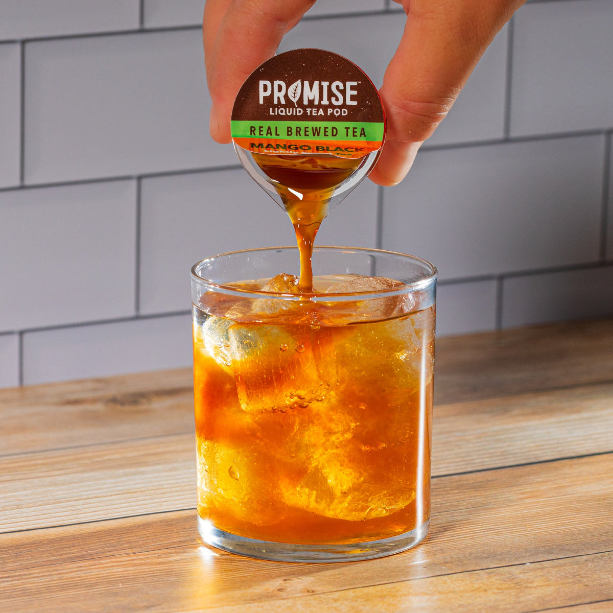 Java House Promise Real Brewed Tea Mango Black, lightly sweetened, in a glass bottle with mango slices and tea leaves visible.