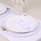 Set of white placemats from Maison Charlo's 7-piece table setting set for 2, includes table runner, napkins, and napkin rings.