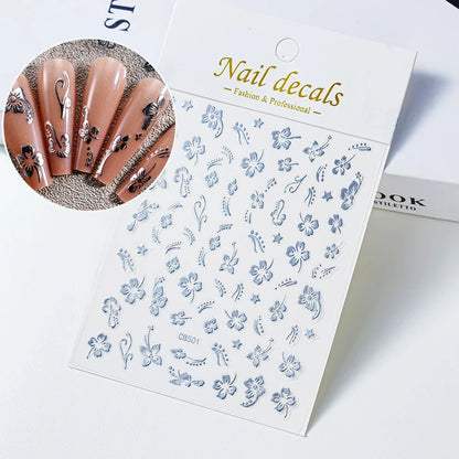 White and black 3D hibiscus flower nail stickers with pink and gold accents, adhesive floral decals for nail art decoration.