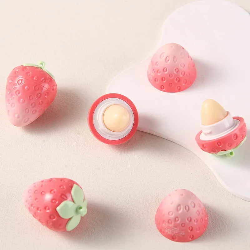 Blushimmer Shiji Strawberry temperature-changing lip balm showing a open tube with soft, glossy lips and fresh strawberries in the background.