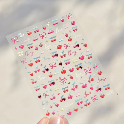 Close-up of Blushimmer cherry-shaped 5D nail art stickers with shiny crystals and bowknot design, ideal for DIY manicure decoration.