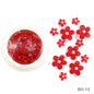 White acrylic flower nail art decorations with mixed size rhinestones, red and blue gems for DIY manicure design.