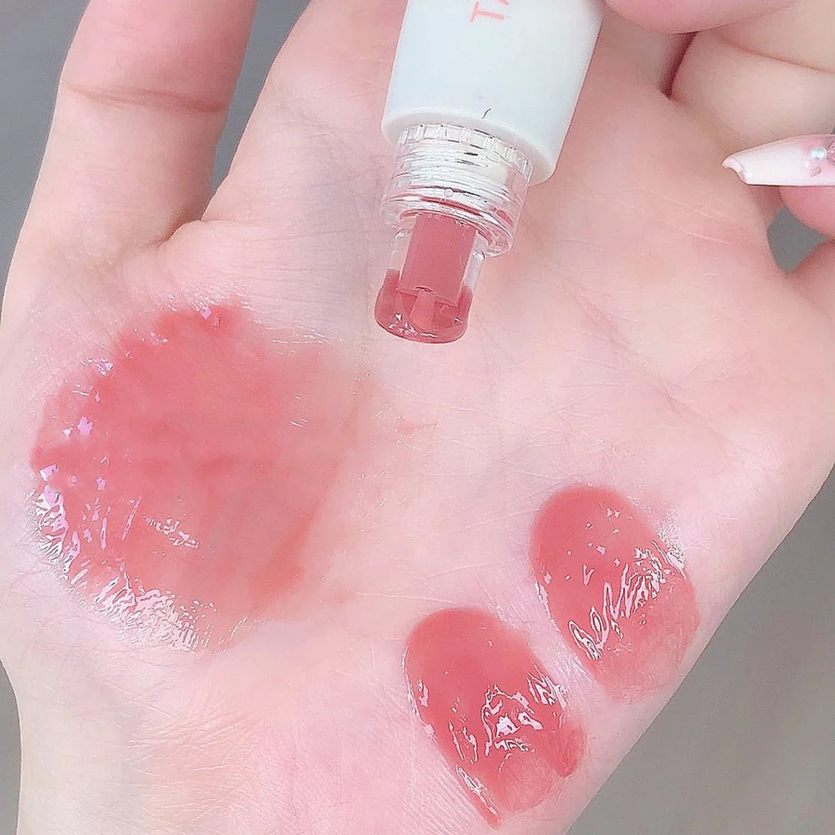 Blushimmer Tatibeauty Lip Jelly Essence Tender Pink hydrating lip gloss with shiny, smooth finish in a clear container.