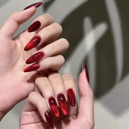 Set of 24 glossy red Cat's Eye press on nails by Blushimmer, almond-shaped false nails with nude color and charm details.