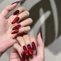 Set of 24 glossy red Cat's Eye press on nails by Blushimmer, almond-shaped false nails with nude color and charm details.