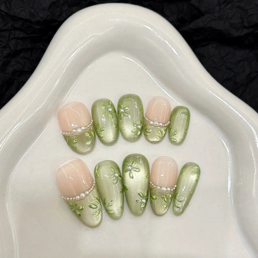 Set of 10 Blushimmer handmade press on nails with green flower print, glitter accents, short oval shape, and cat eye design.