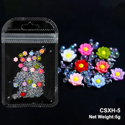 White acrylic flower nail art decorations with mixed size rhinestones and colored gems for DIY manicure embellishments.