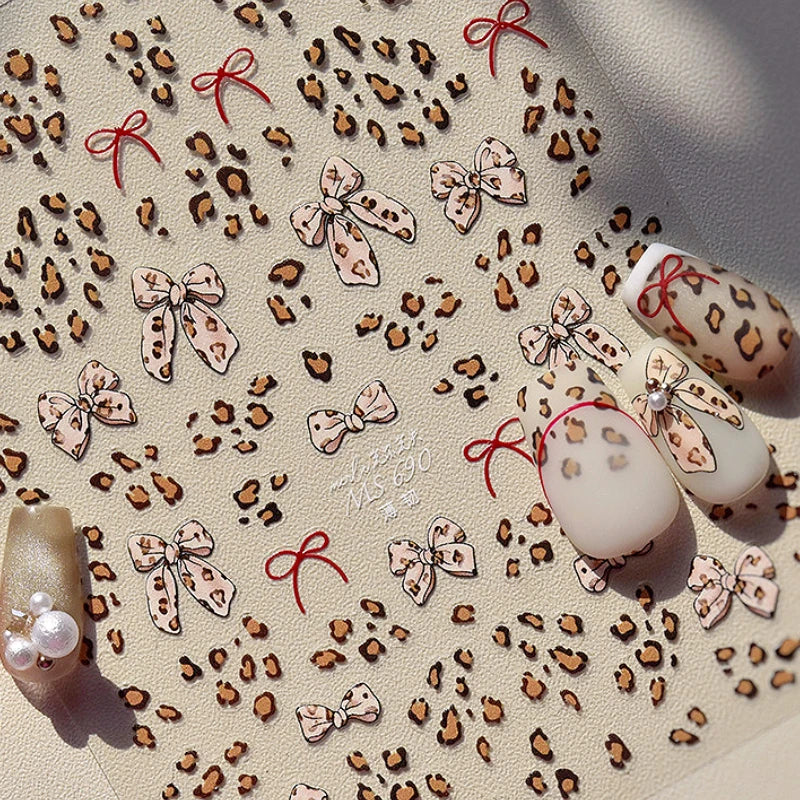White and black nail art stickers with rhinestones, pearls, and leopard print bowknot designs for manicure decoration by Blushimmer.
