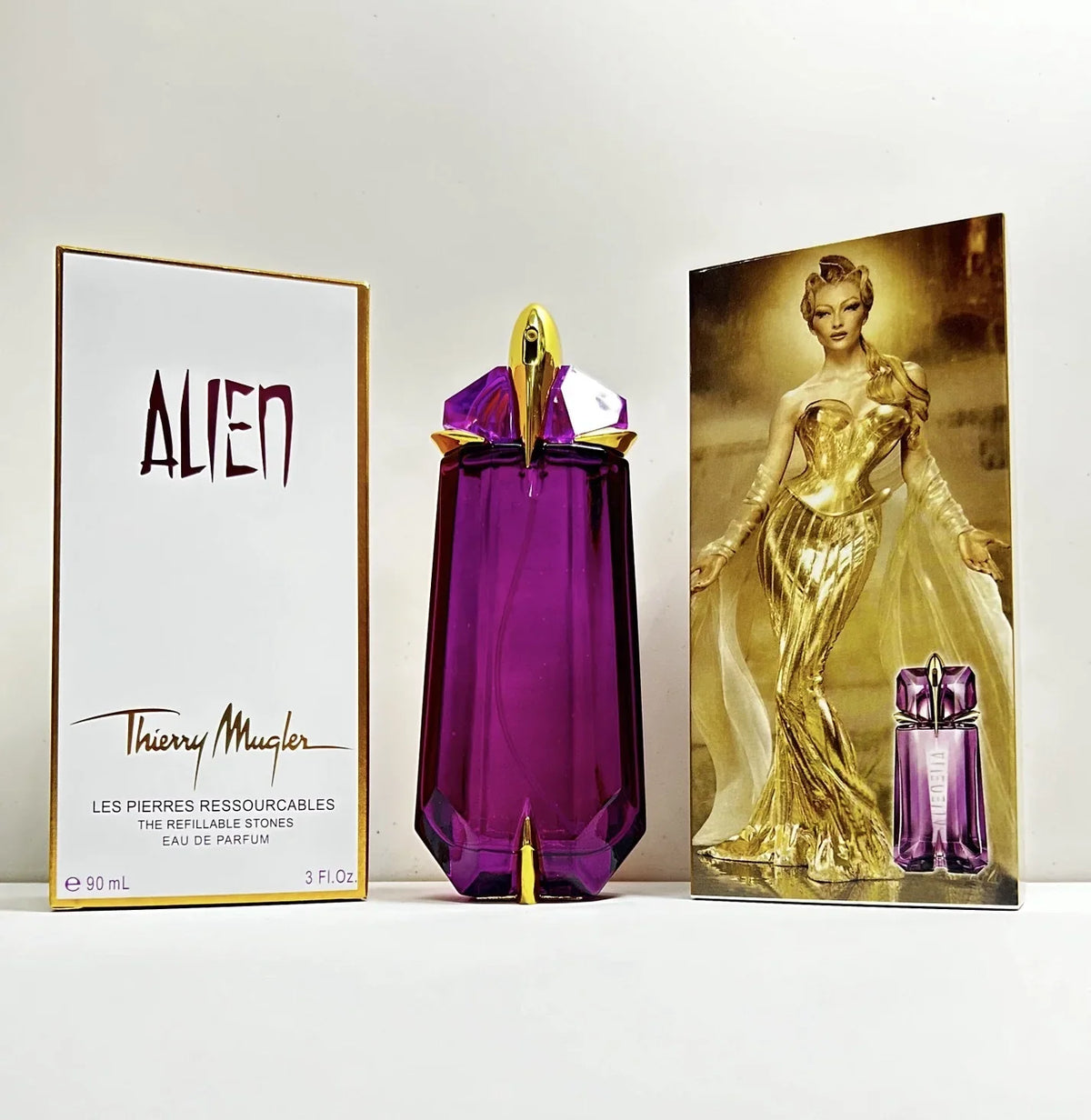 Thierry Mugler Alien perfume bottle in purple, gold, and red with a sleek design, 90ml concentrated women's fragrance by Blushimmer.