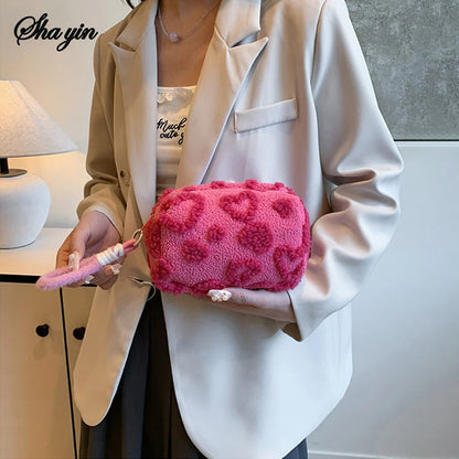 Soft blush pink plush makeup bag with handle, featuring a love print, perfect for travel cosmetic storage and organization.