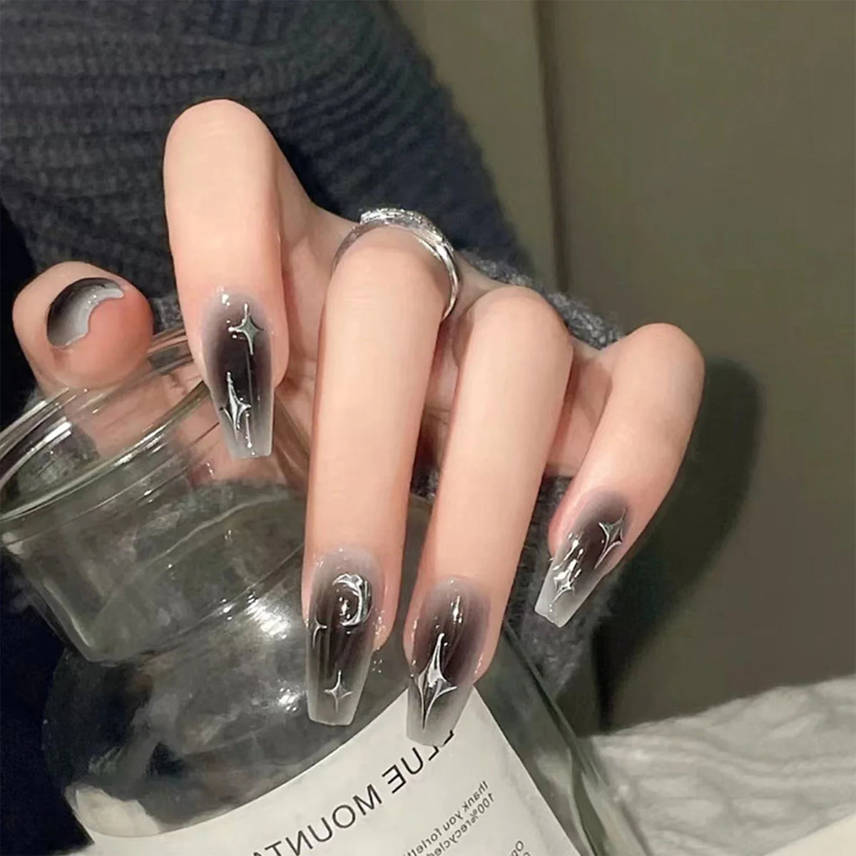 Set of 24 Y2K star press-on nails by Blushimmer featuring gradient black mid-length coffin tips with moon designs.