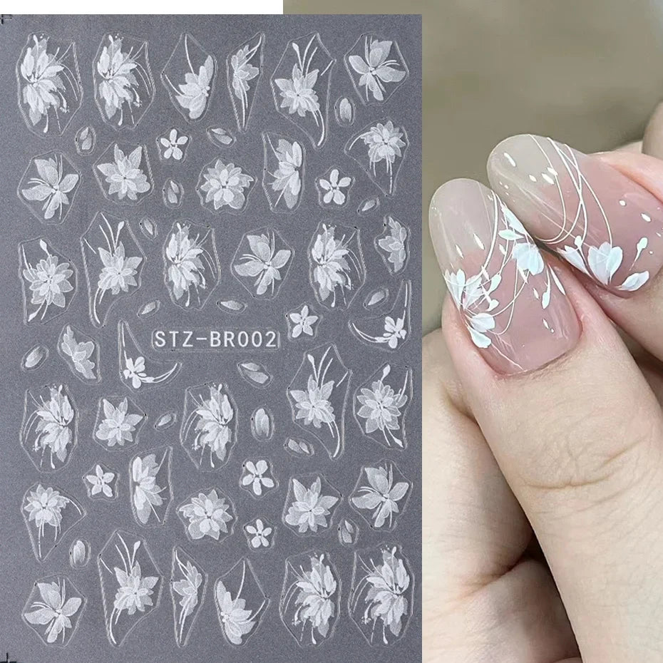 Close-up of Blushimmer 3D white flower nail art stickers with cute floral designs and adhesive backing for DIY nail decorating.
