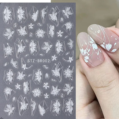 Close-up of Blushimmer 3D white flower nail art stickers with cute floral designs and adhesive backing for DIY nail decorating.