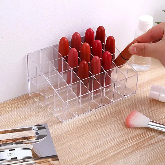 Transparent lipstick storage rack by Blushimmer showing organized plastic box with multiple lipstick compartments on a desktop.