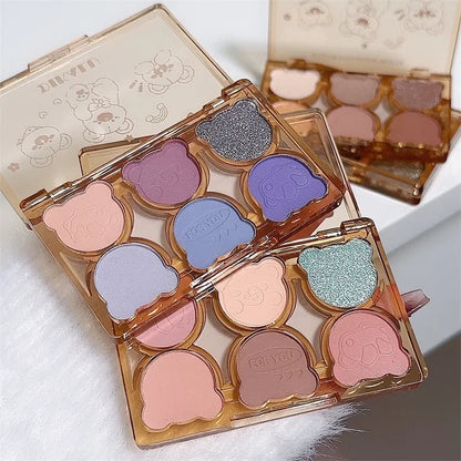 Blushimmer 6-color matte and shimmering eyeshadow palette with smoky gray, red, black, and wine shades for eye makeup.
