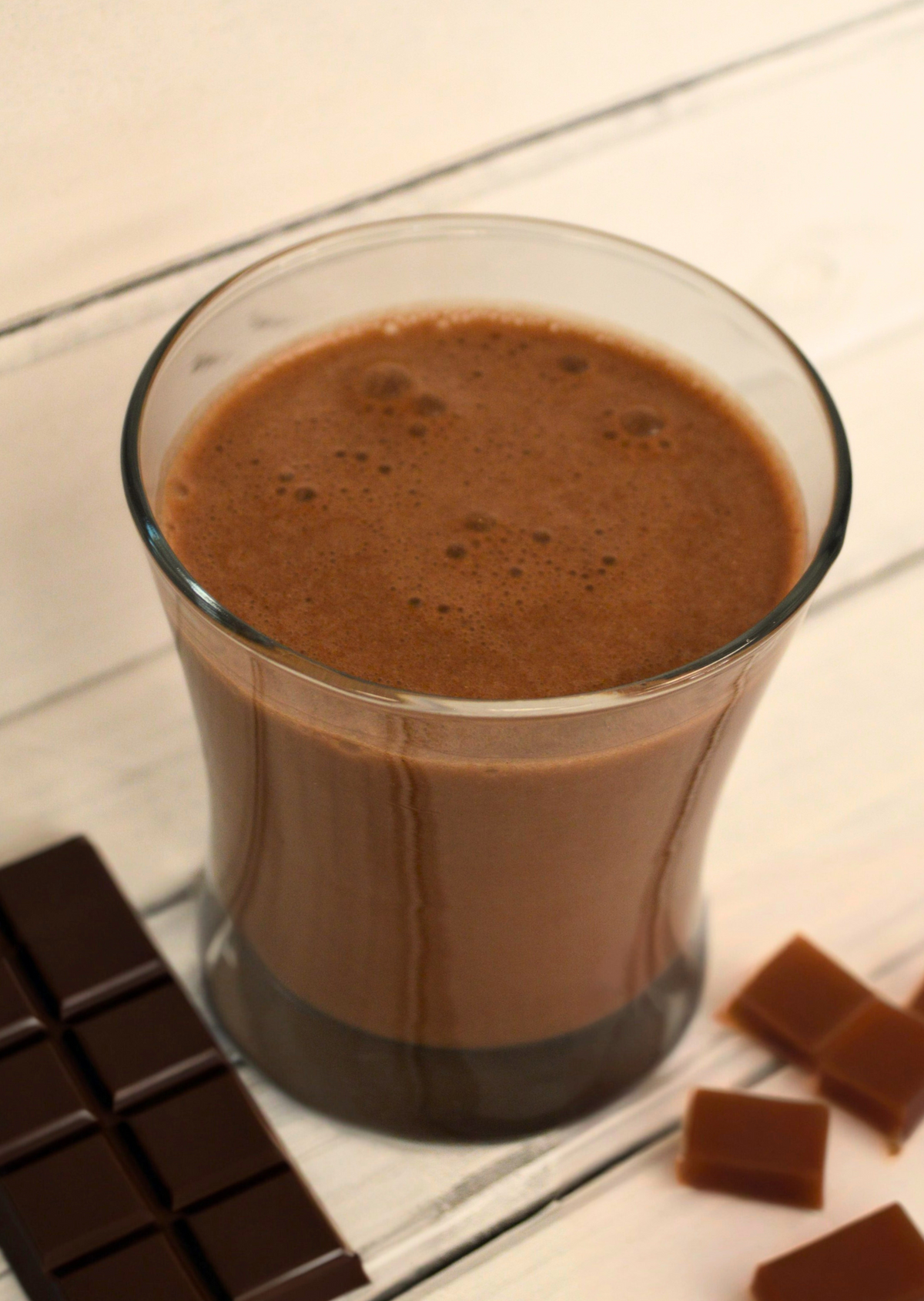 Creamy salted caramel protein shake by AmBari Nutrition in a clear glass, topped with caramel drizzle and a sprinkle of sea salt.