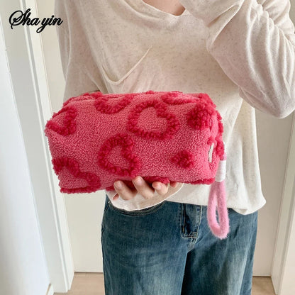 Soft blush pink plush makeup bag with handle, portable travel cosmetic storage, love print design, ideal for organizing pencils and toiletries.