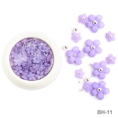 White acrylic flower nail art decorations with mixed size rhinestones and colored gems for DIY manicure designs.