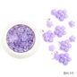 White acrylic flower nail art decorations with mixed size rhinestones and colored gems for DIY manicure designs.