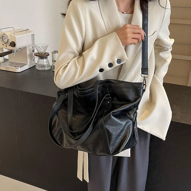 Black leather women's tote and shoulder crossbody bag by OBA, featuring a spacious shopper design and versatile carry options.