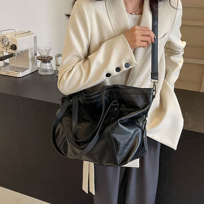 Black leather women's tote and shoulder crossbody bag by OBA, featuring a spacious shopper design and versatile carry options.