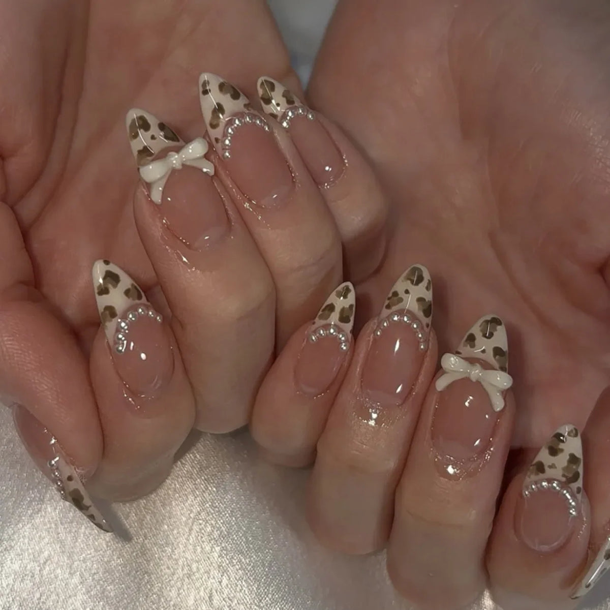 Blushimmer 3D bowknot pearl almond fake nails with leopard French nude design, detachable and press-on for fashionable nail art.