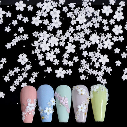 White acrylic flower nail art decorations with mixed size red and blue rhinestones for DIY manicure design by Blushimmer.