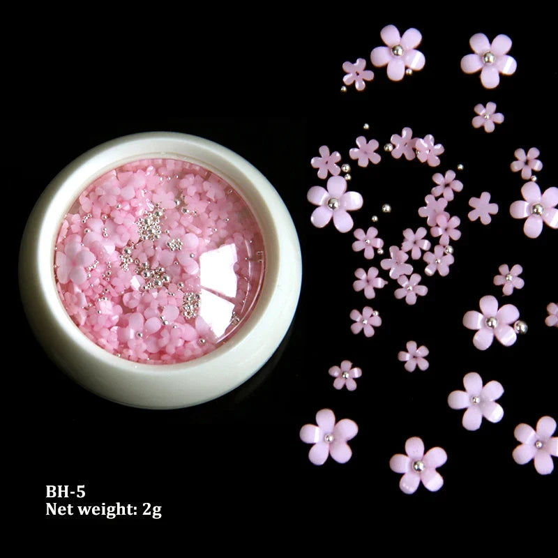 White acrylic flower nail art decorations with mixed size rhinestones and colorful gems for DIY manicure designs.