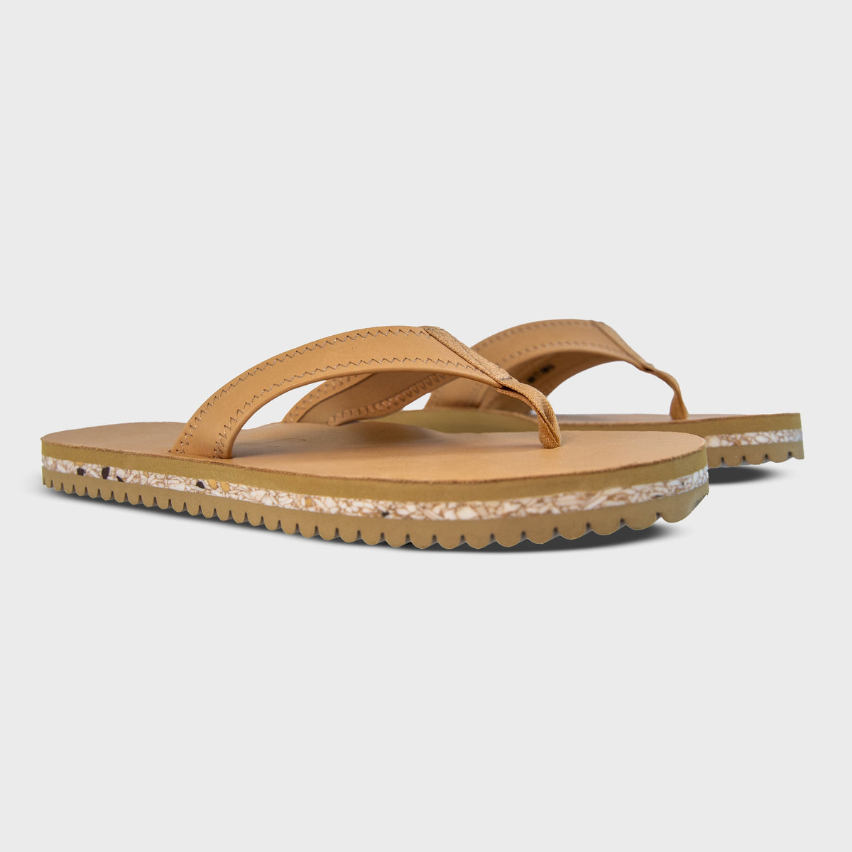 Pair of Fleks Seagrove Flip Flops in sand color, side profile view showing comfortable straps and casual summer footwear.