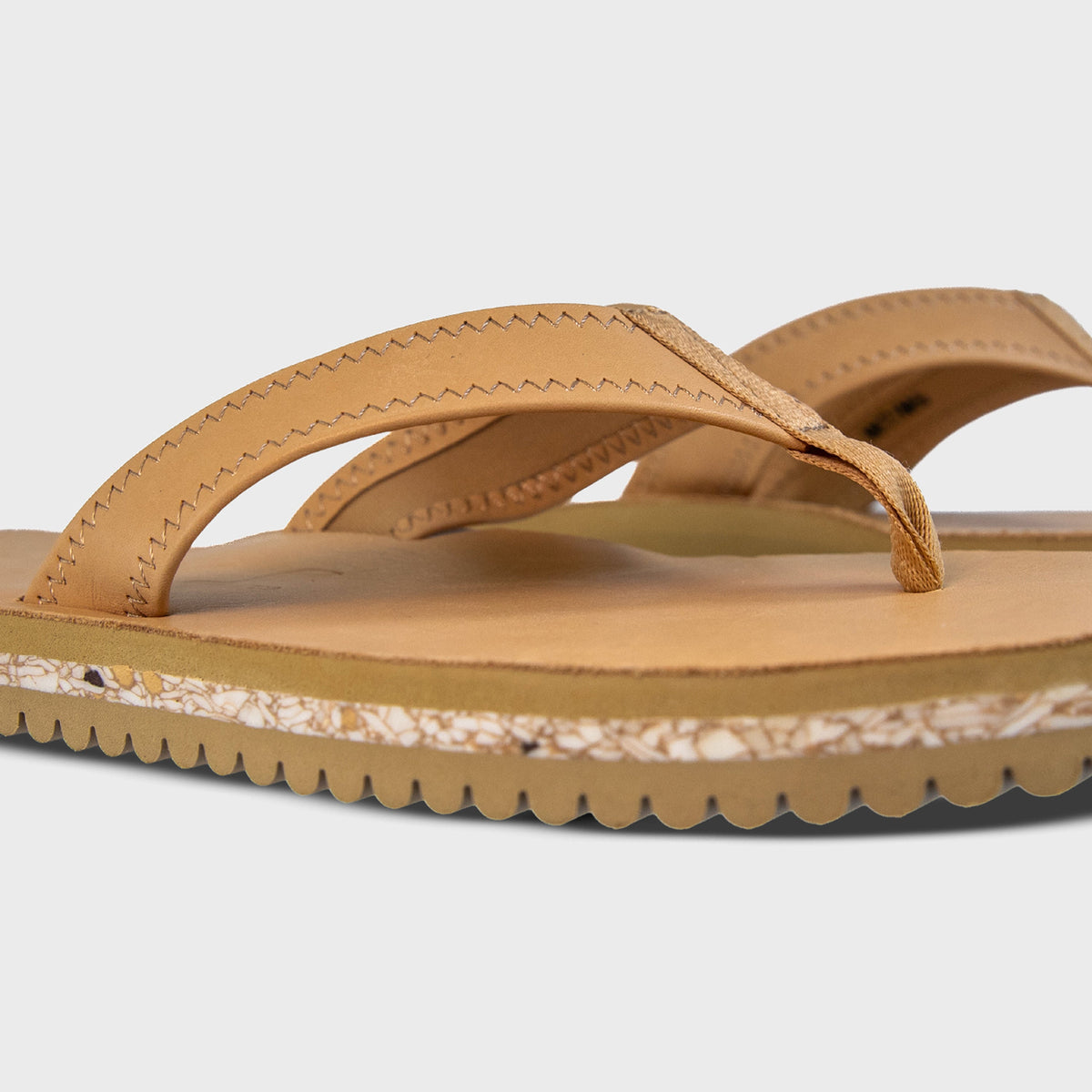 Pair of Fleks Seagrove Flip Flop sandals in sand color, showing side profile and angled view.