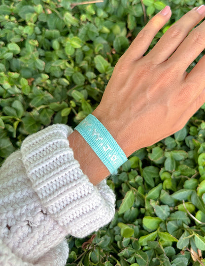 Teal WWJD embroidered wristband bracelet by Elevated Faith with stitched lettering on fabric band.