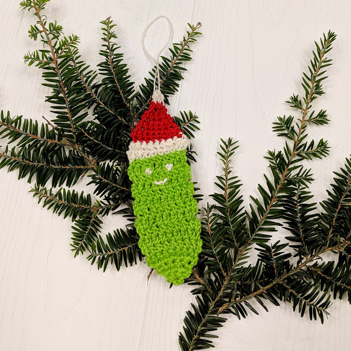 Crochet Christmas pickle ornament with colorful yarn, handmade holiday decoration, created by Darn Good Yarn for festive decor.