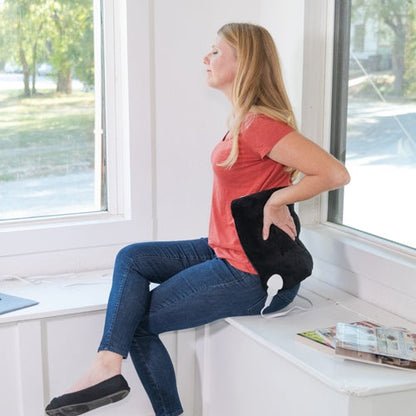 iReliev weighted heating pad for hot and cold therapy, shown in a lifestyle setting with person applying it to shoulder.