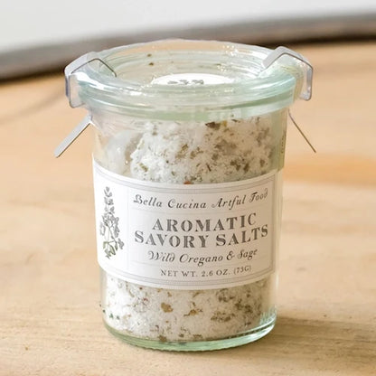 Jar of Bella Cucina Wild Oregano & Sage Savory Salt in a clear glass container with a spoon, showcasing the seasoned condiment.