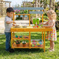Yellow wooden outdoor mud kitchen for kids with wheels, featuring play sinks, storage, and pretend cooking accessories.