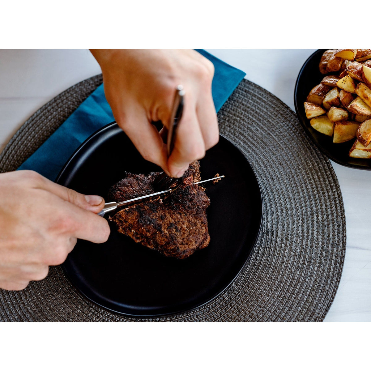 Set of 8 Dura Living gray steak knives with sleek handles, arranged on a wooden cutting board for serving.