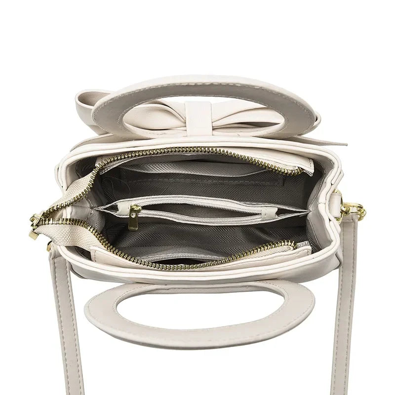 Casual women's handbags featuring cute bow designs in black, white, blue, and khaki PU leather, with shoulder and underarm styles.