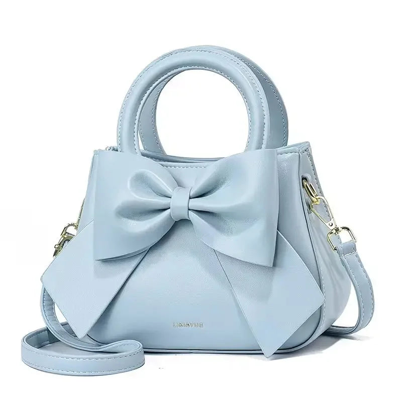 Fashion casual women's handbags featuring cute bow designs in black, white, blue, and khaki with PU material and shoulder straps.