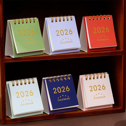 Mini 2026 desk calendar by BackupMyFilesNow.com, featuring monthly planner, office supplies, and decorative desk accessories.