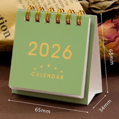 Mini 2026 desk calendar by BackupMyFilesNow.com, featuring monthly planner, office supplies, and decorative desk accessories.