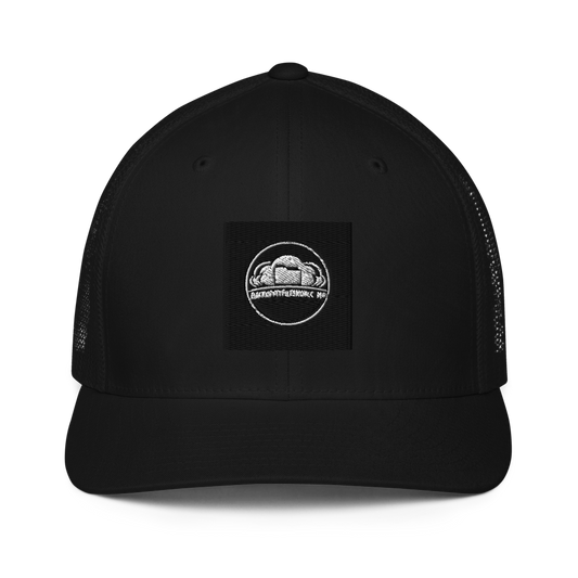Black Flexfit 6511 closed-back trucker cap with mesh back and adjustable strap, featuring a structured front panel.