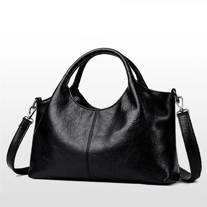 Large black women's handbag with golden hardware, detachable crossbody strap, zipper closure, elegant design, and spacious interior.