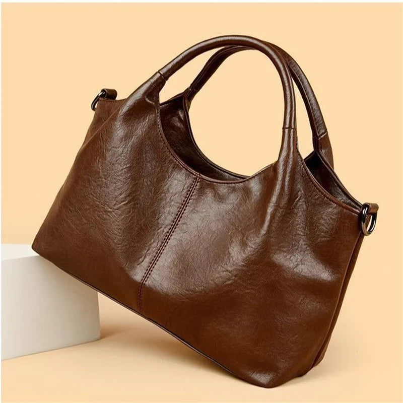 Black women's handbag with large capacity, elegant design, detachable crossbody strap, golden hardware, and zipper closure.