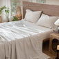 4-piece pure linen bed sheet set with flat sheet, deep pocket fitted sheet, and pillowcases in natural flax color.