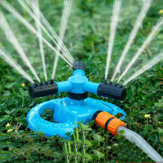 360-degree automatic rotating sprinkler nozzle in use, watering a garden lawn with a fine water spray for irrigation.