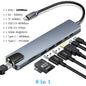 Gray USB 3.0 Type C hub with HDMI 4K, Ethernet, VGA, headphone jack, and PD 100W charging port on a clean surface.
