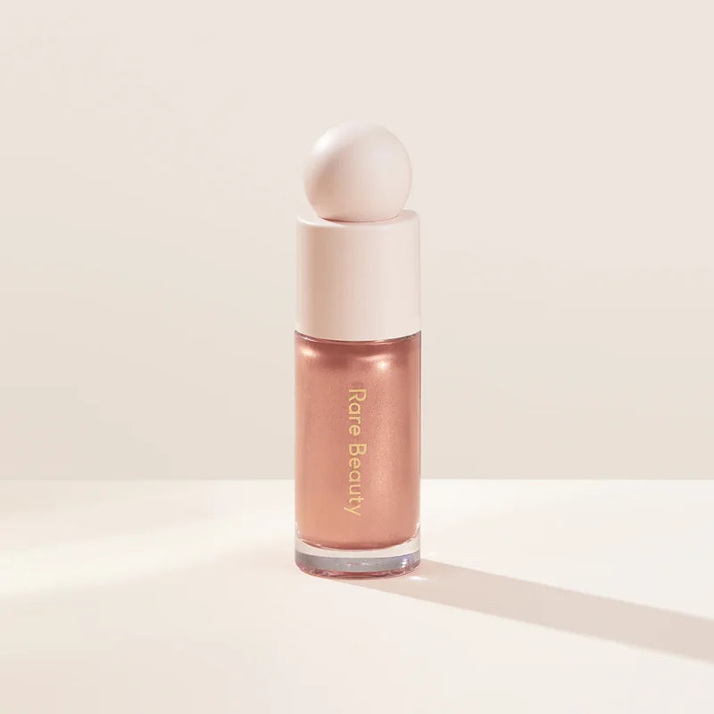 Rare Beauty liquid blush cream with dewy finish, blendable multi-use cheek and lip tint in a portable makeup container.