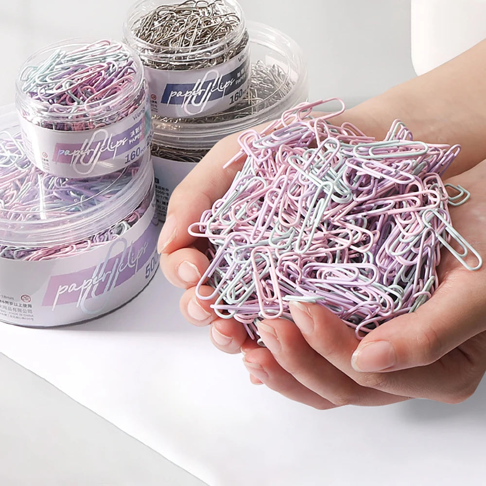 Color paper clips and large file bookmarks in a storage box, ideal office supplies for organizing papers and stationery.